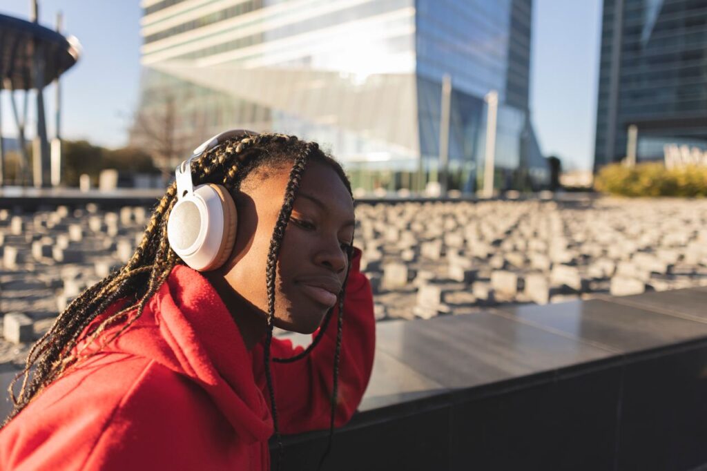 Young black woman listening to music outside on headphones