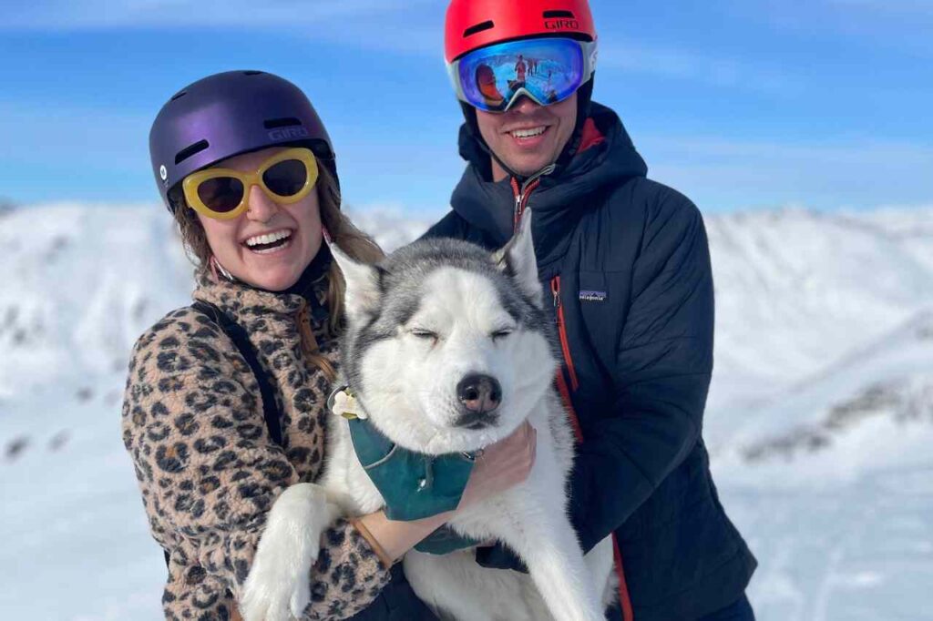 Danielle on a ski trip with a man and a Husky dog.