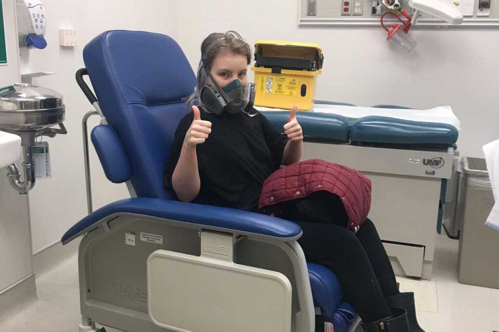 Madison in the hospital wearing a gas mask, battling Multiple Chemical Sensitivity (MCS).