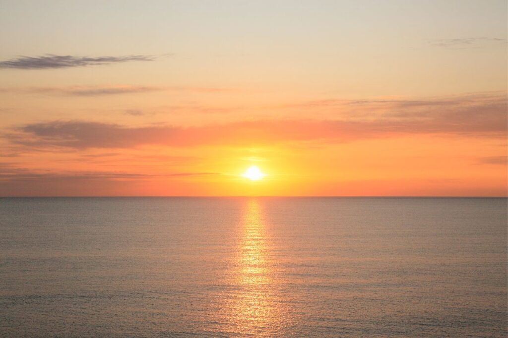 The sun peeking out over the ocean horizon, symbolizing hope as Mel began her healing journey from Lyme Disease.
